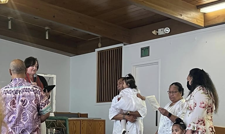 two Samoan children being baptized with parents and adults.