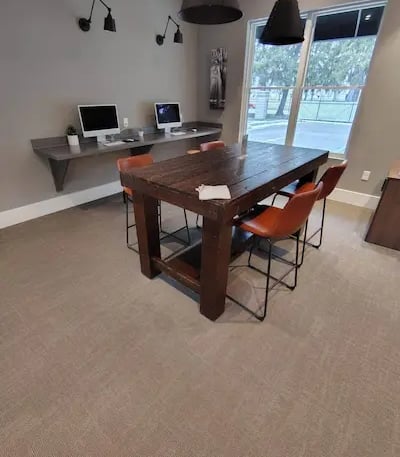 Picture of an office with two computer monitor and a table with four red chairs