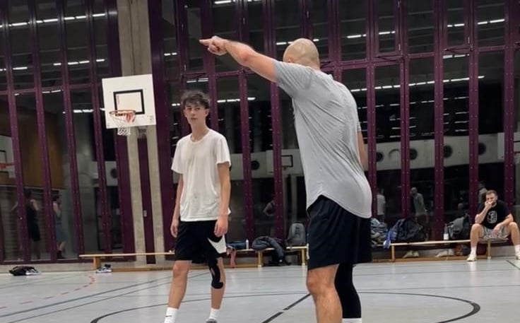 alt="Basketball coach instructing youth player during training."