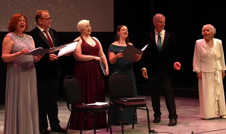 A group of diverse singers in formal attire performing a choral concert on a theater stage.