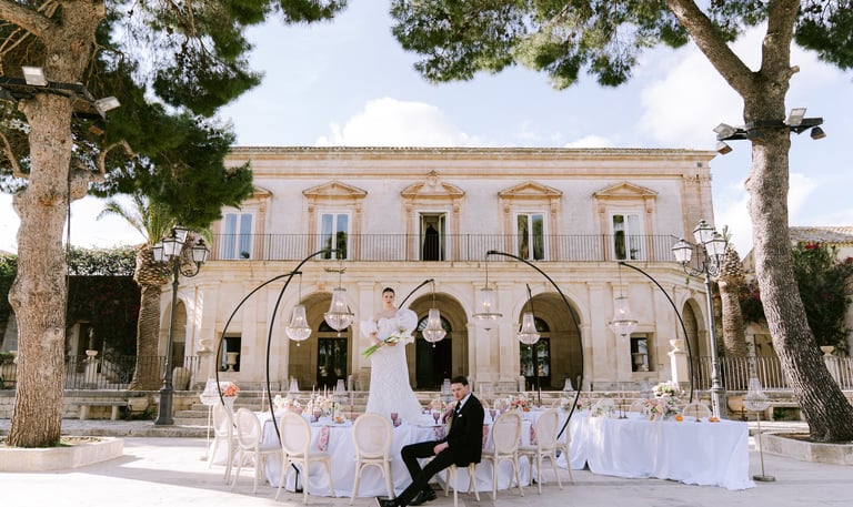 villa adibita a matrimonio con la sposa sul tavolo in piedi e lo sposo seduto su una sedia