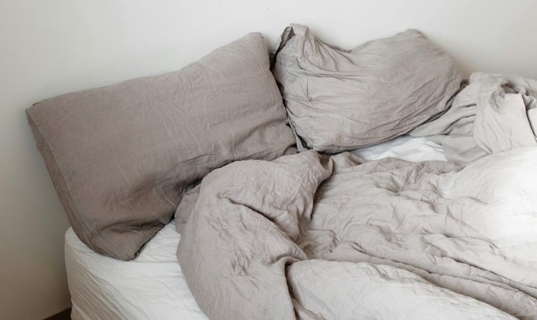 a single bed that is unmade with two pillows