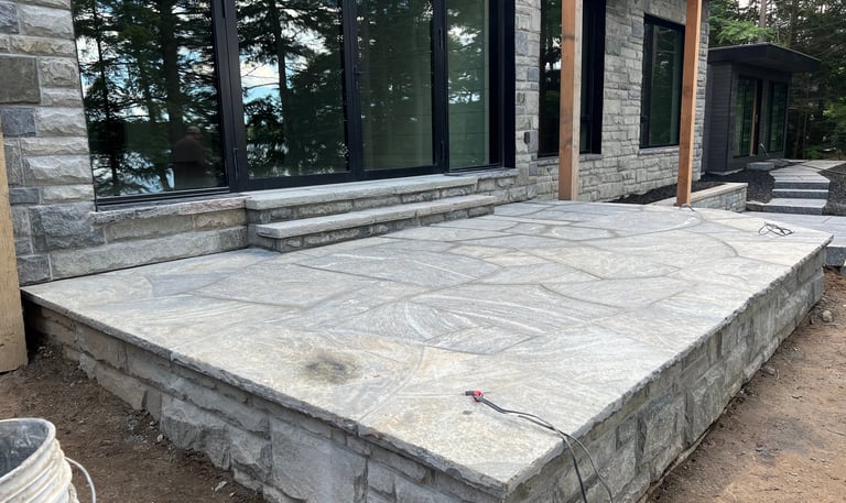 Custom natural flagstone patio and stone retaining wall outside a modern lakeside home.