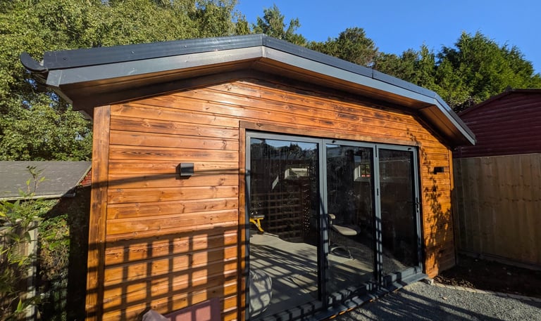 A modern insulated wooden garden gym with anthracite grey bifold doors in a garden