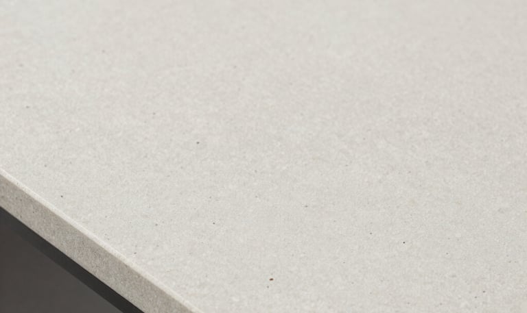 Close-up of polished white marble slabs with subtle gray veining stacked neatly in a sunlit warehouse.