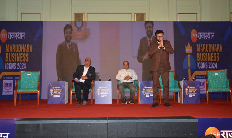 Speaker addressing an audience at a business event with panelists on stage.
