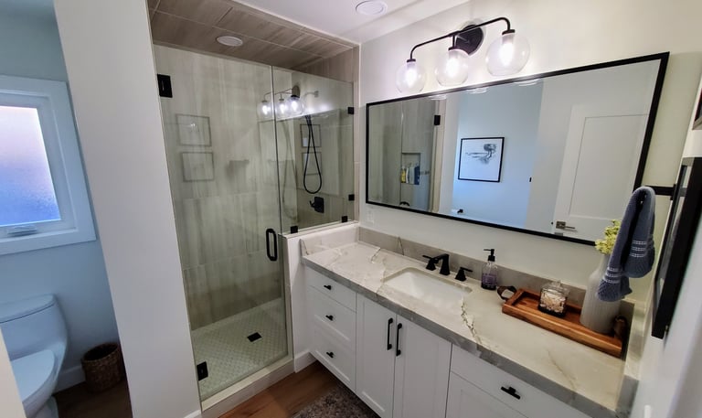 Renovated bathroom with large mirror and black hardware. Colorado Springs bathroom remodel.
