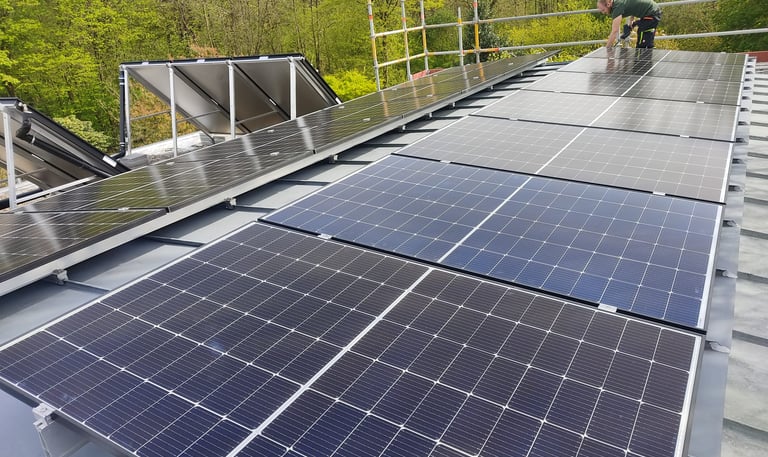 Ein Mann steht auf einem Dach mit Solarpaneelen.