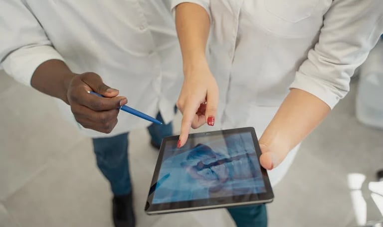 un médico con un bolígrafo y una Tablet enseñando una radiografía dental a otro odontólogo