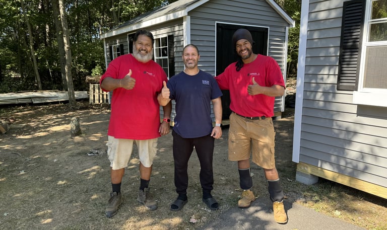 Satisfied customer standing with Imperial Custom Sheds team after shed installation