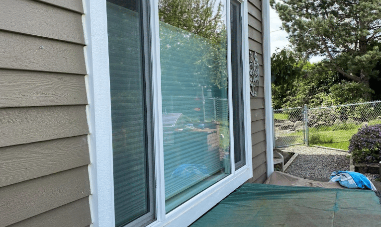 Exterior view of a house showing large sliding glass doors and siding.