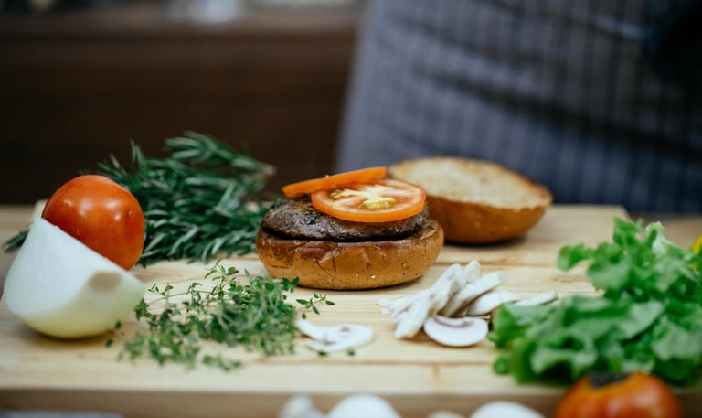 chef making a delicious burger with beef, tomato, mushrooms and onions.