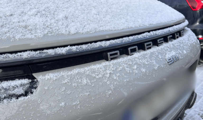 an Enlab Porsche car with a hood on it and a car parked in front of it