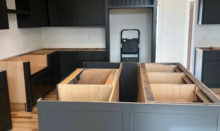 Modern kitchen remodel featuring dark gray cabinets and a large island with hardwood floors.