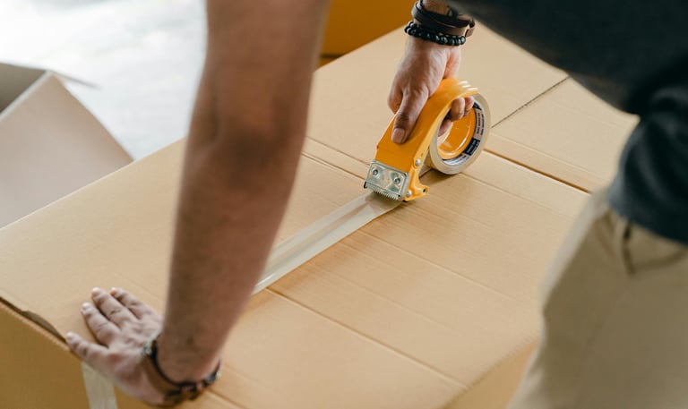 person putting tape on a moving box