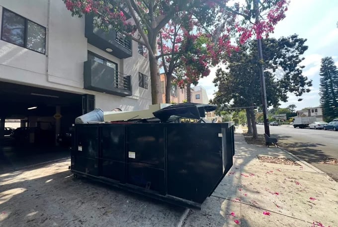 a dumpster sitting on the sidewalk next to a building