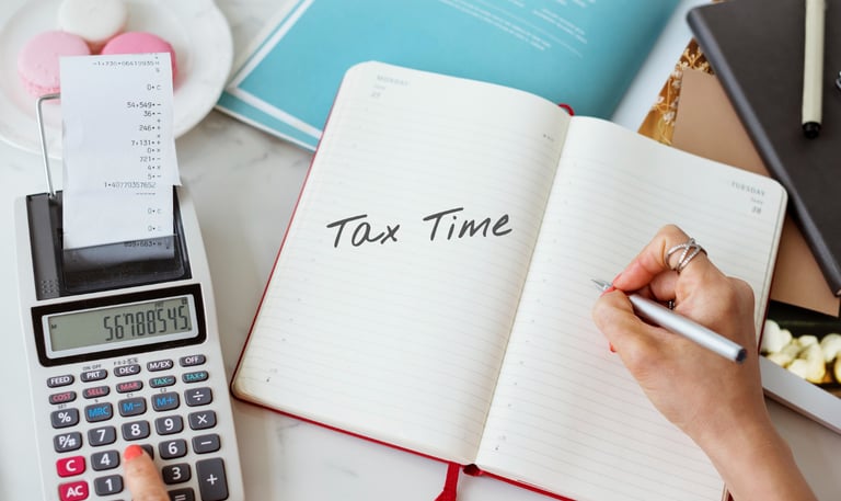 a person writing tax tax calculations on a notebook