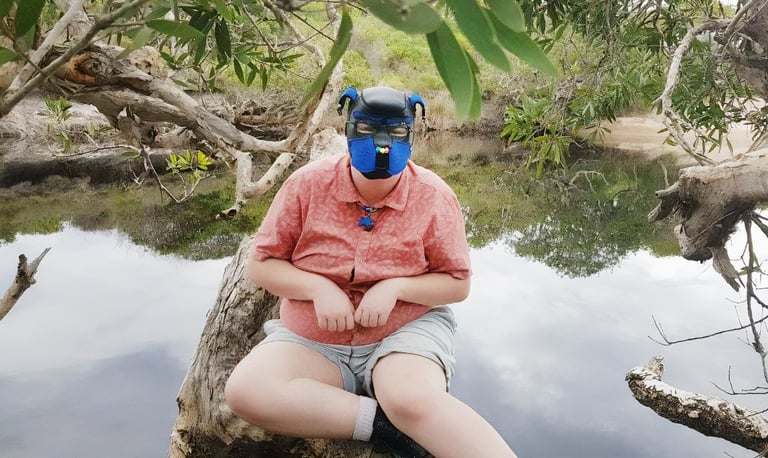 Person posing on a log wearing a pup mask.