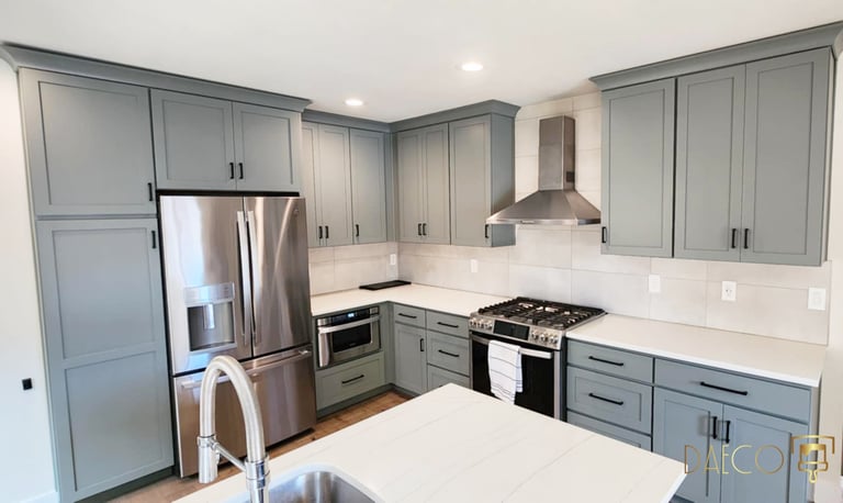a kitchen with a stainless steel refrigerator and a stove top painted cabinets