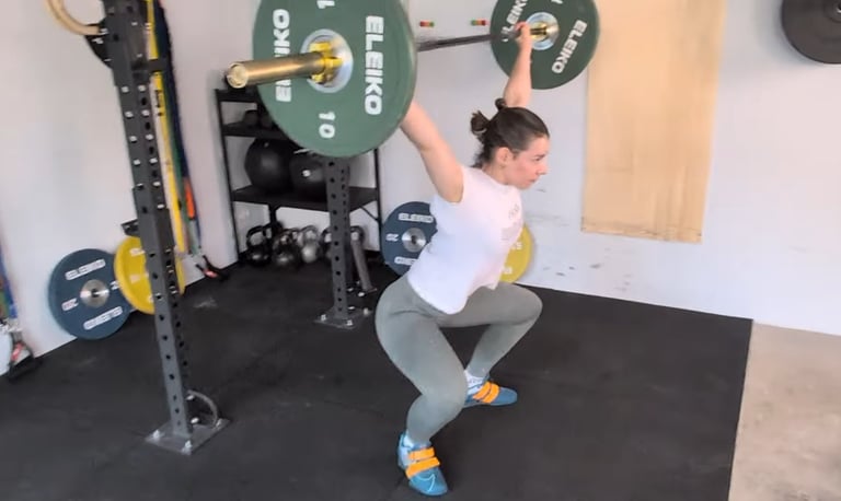 Eine Frau führt ein Reißen (Snatch) mit einer Langhantel aus.