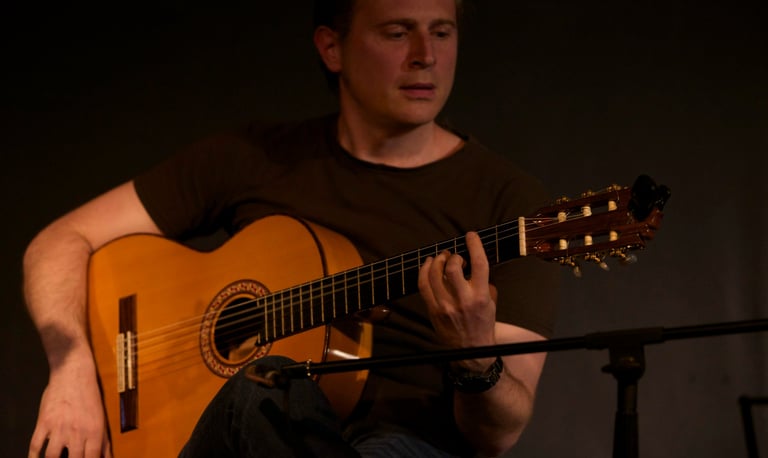 a man playing a guitar in a dark room