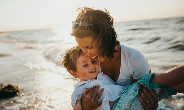 Mum and child playing at the beach laughing and enjoying life