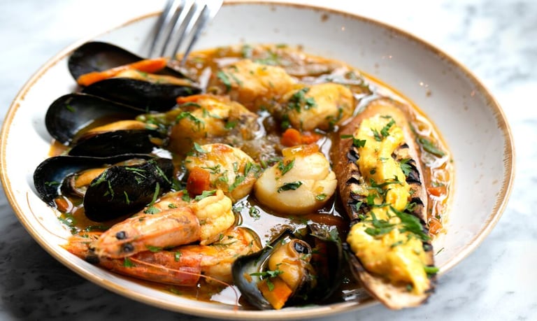 Traditionelle Bouillabaisse in Marseille, serviert dampfend im Teller mit frischem Brot und Aioli, Meerblick im Hintergrund,