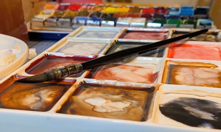 Waterverf palet met penseel en aquarel napjes, gemengde kleuren op een bord