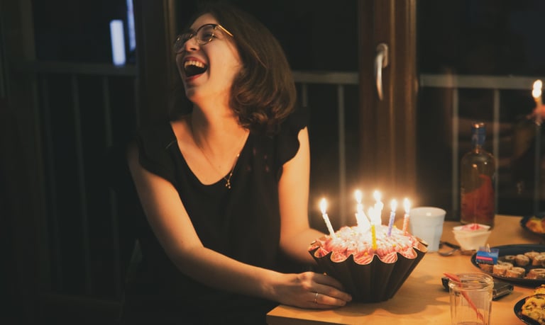 une femme rit aux éclats devant son gateau d'anniversaire, par zohra Elmes 