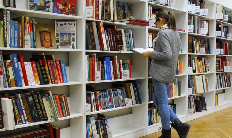 must read books on longevity - a woman is standing in front of a bookcase