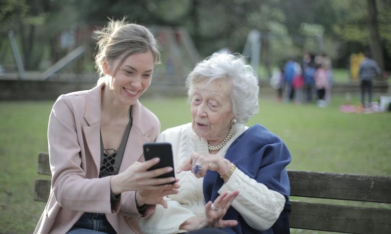 relationships and aging - two women sitting on a bench with a cell phone