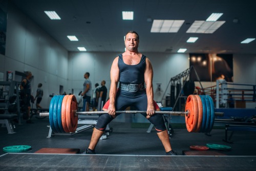 a man in a black top performing the deadlift