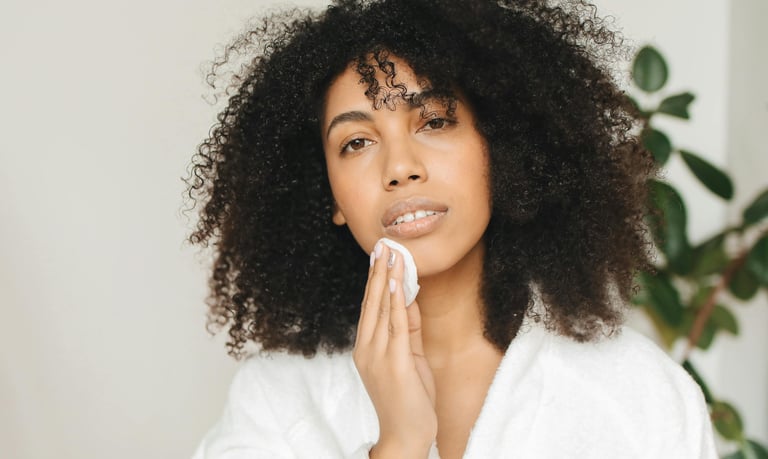 A woman in a robe holding up a face cotton pad