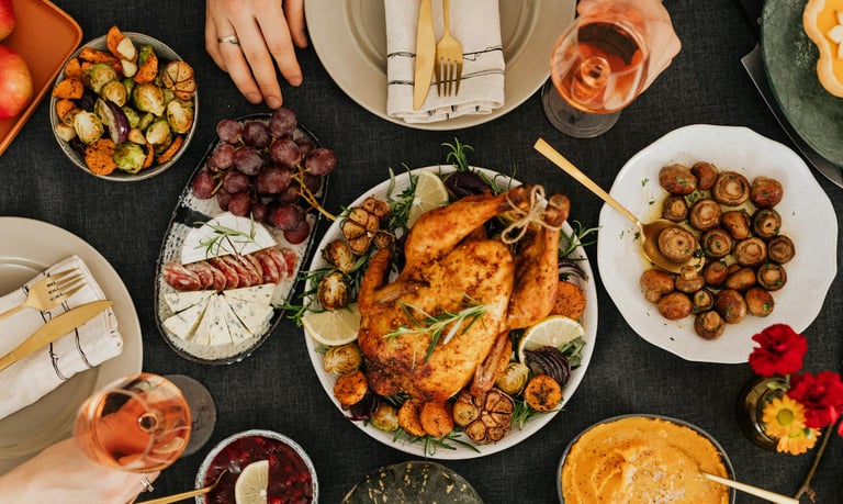 A holiday food spread with turkey, cheese, grapes, mushrooms, brussel sprouts, squash, cranberry sauce and wine