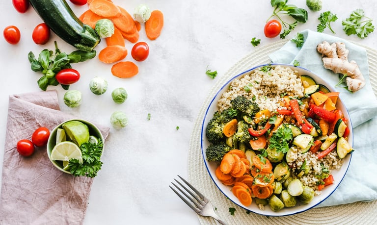 A colorful vegetable salad bowl with carrots, broccoli, cucumber, zuchinni, quionoa, and cherry tomatoes