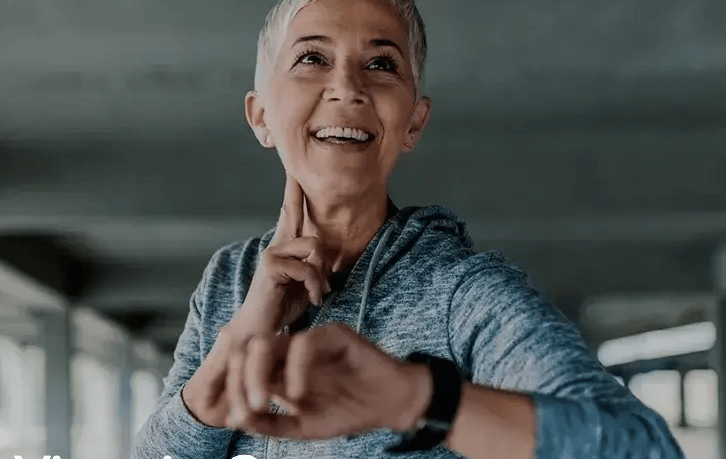 woman smiling while checking her pulse after a workout.