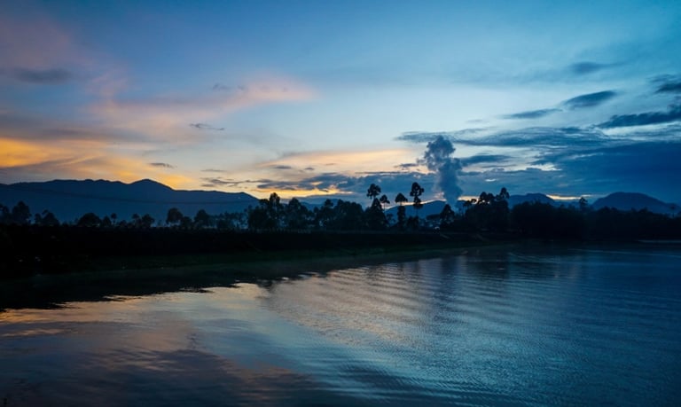 Potret Situ Cileunca saat matahari terbenam, menampilkan refleksi langit senja di permukaan danau, siluet pegunungan, dan pep