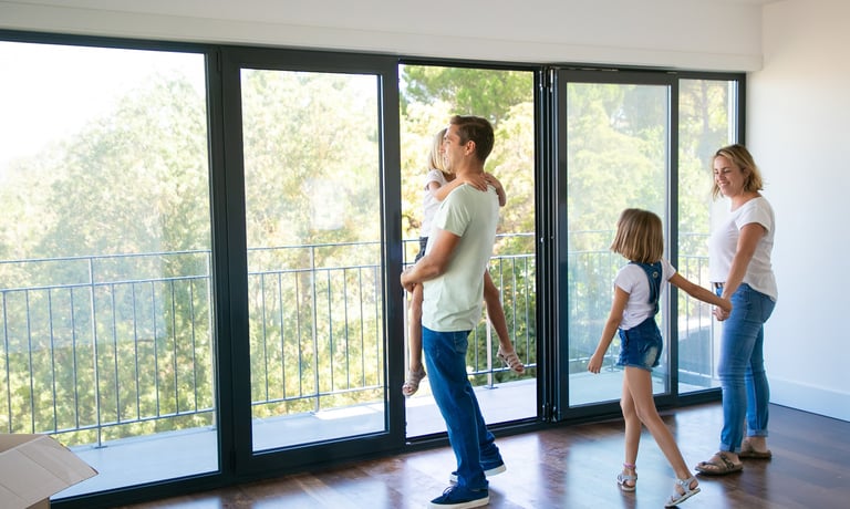 Familia disfrutando de puerta balcón plegable en aluminio con baranda de vidrio — Aberturas Gala GBA