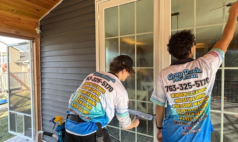 Two Gray Duck Pro Wash employees performing professional window cleaning using mop and squeegee on a