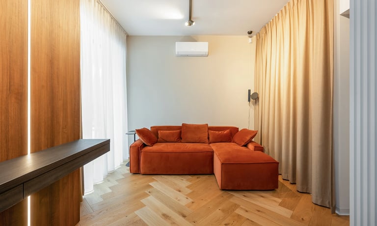 Nowoczesny salon z pomarańczową sofą narożną, drewnianą podłogą i zasłonami