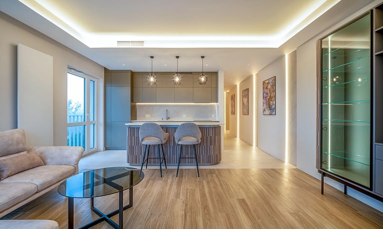 Nowoczesny salon z aneksem kuchennym, wyspa z dwoma hokerami i oświetleniem LED.