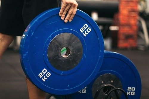 a person holding a blue and white plated weight plate