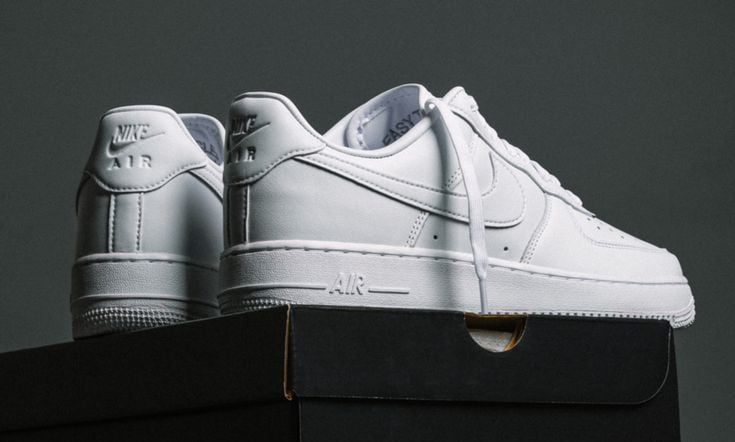 Zapatillas Nike Air Force 1 blancas de cuero de caña baja sobre cajas de zapatos negras.