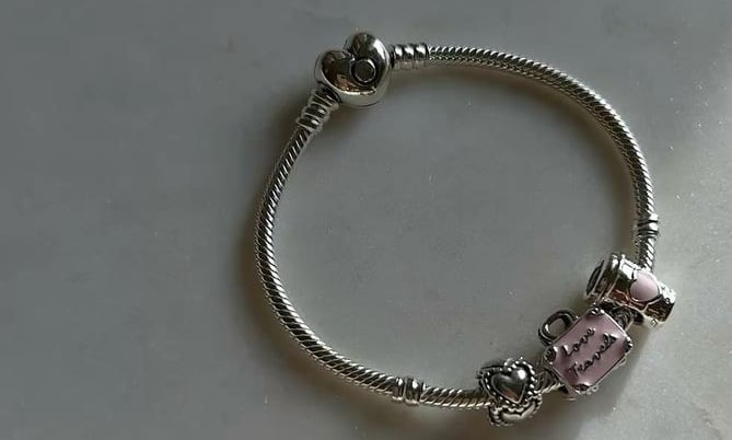 Pulsera de dijes Pandora de plata con cierre de corazón y dijes.