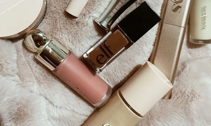 Productos de maquillaje de e.l.f., putty, Halo Glow y Rare Beauty sobre una alfombra.