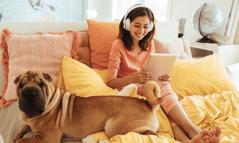 a woman sitting on a bed with a dog and a laptop