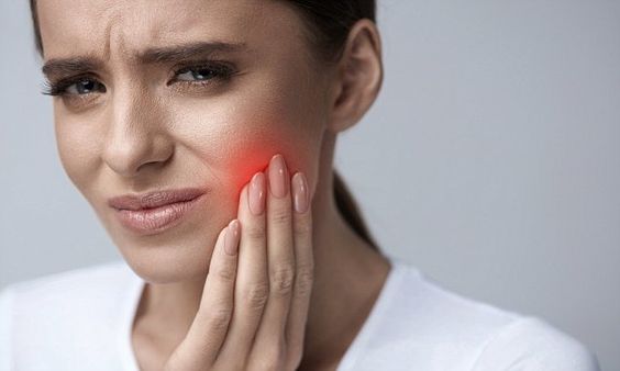 Mulher com a mão no rosto ilustrando sintomas de bruxismo avaliados por dentista na Lapa PR.