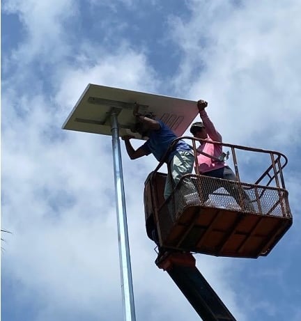 Technicians performing high-altitude electrical wiring on a solar panel.