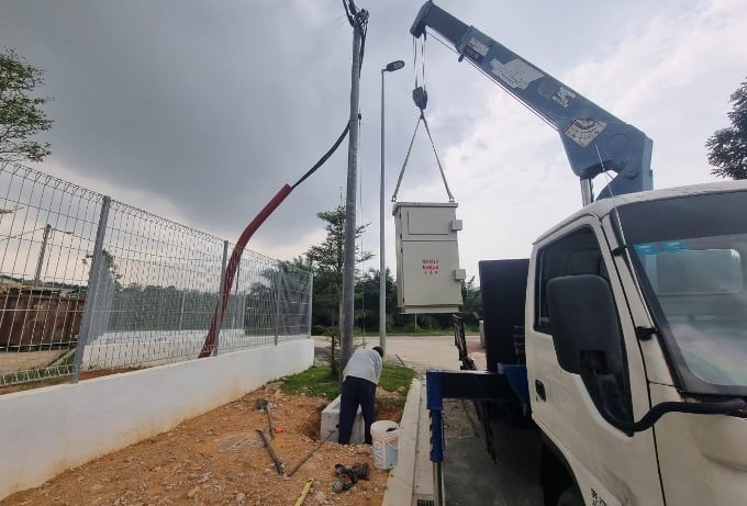 Installation of an electrical meter kiosk using a crane at a secured facility site, demonstrating professional electrical eng
