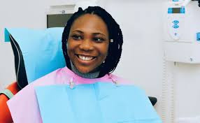 Souriante femme en fauteuil lors d'un contrôle dentaire professionnel.